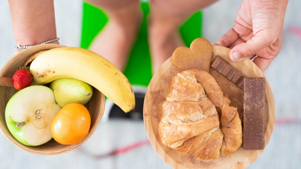 close up of woman holding to plates with two different types of food - unhealthy and healthy food