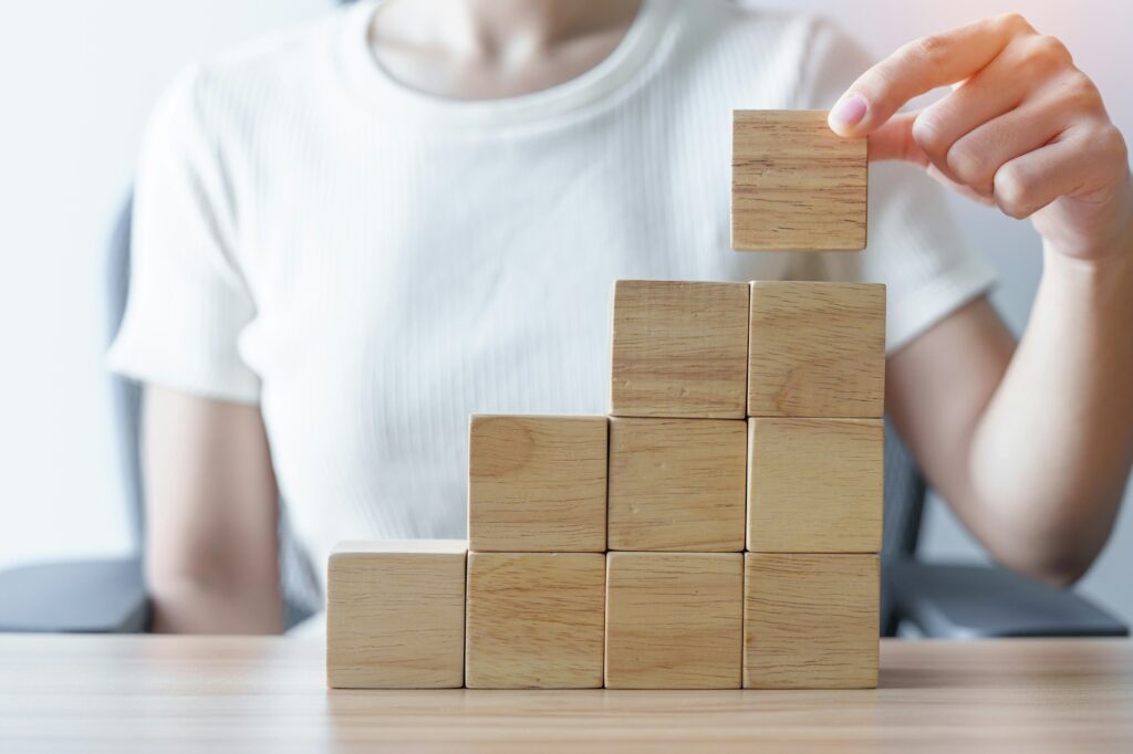 Woman hand placing wood block on the building