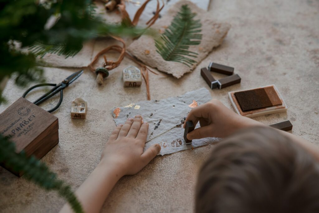 DIY of gift card with craft paper from recycled materials and plants. Boy stamping by wooden stamps