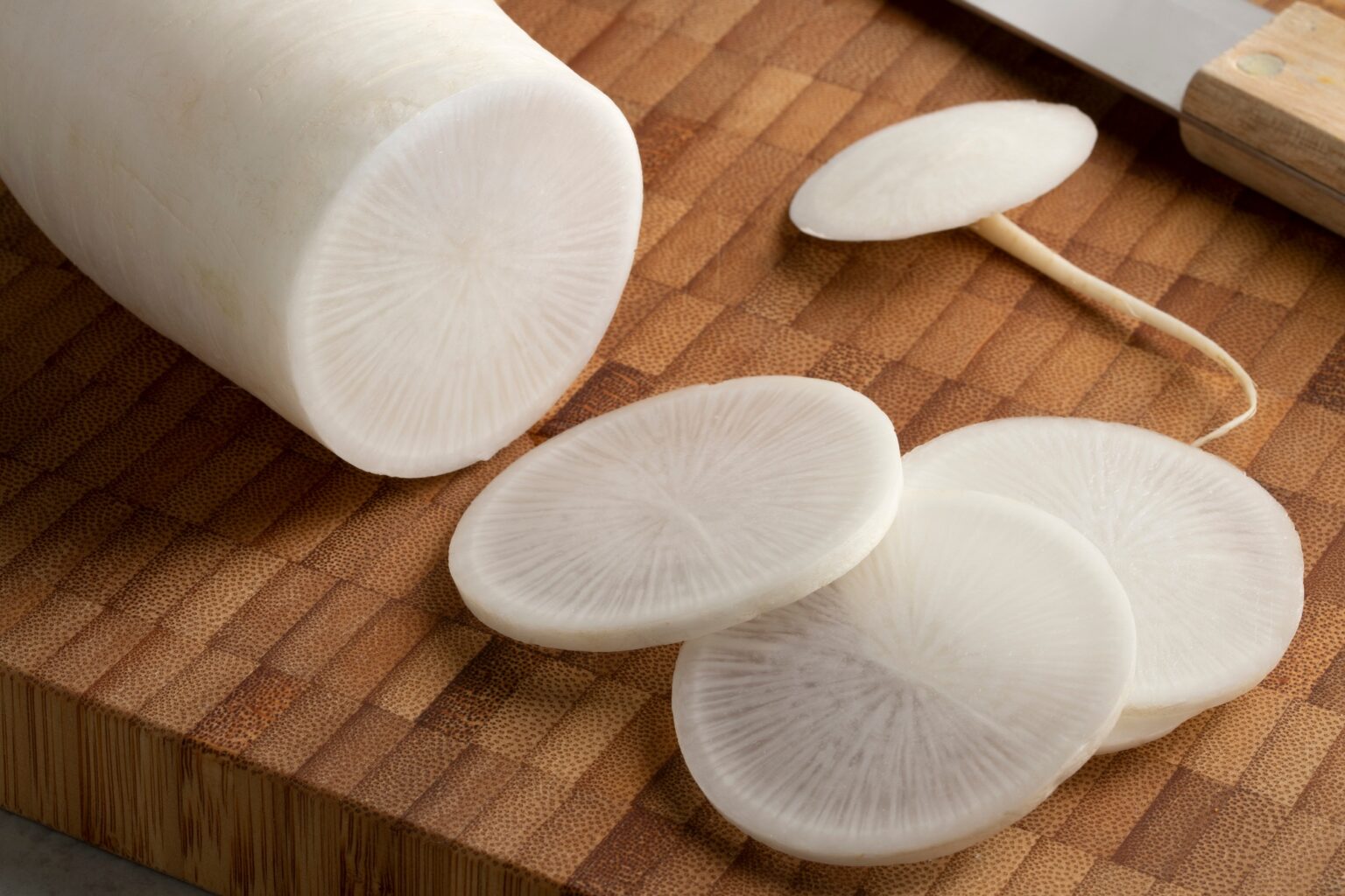 Fresh white daikon radish and slices on a cutting board